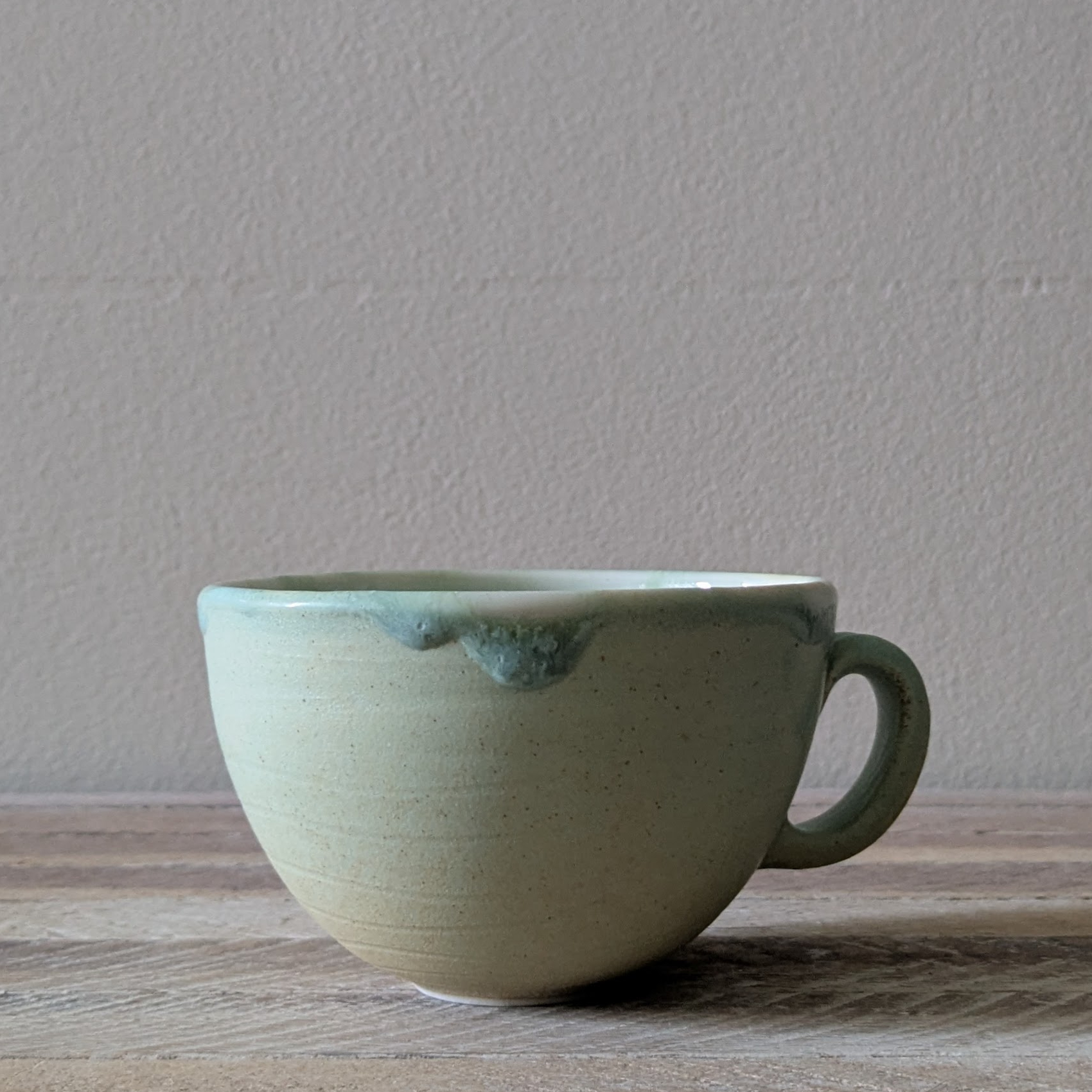 Porcelain cup for tea or coffee with smooth matte green glaze with soft hints of yellow