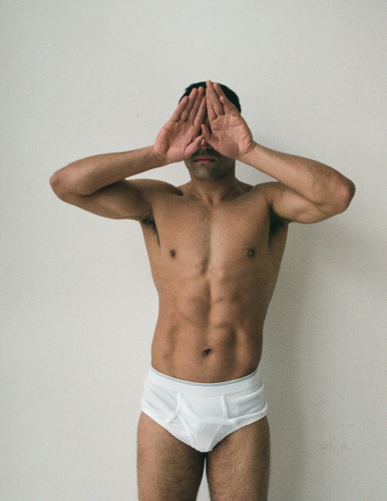 Handsome shirtless man covering eyes with hands