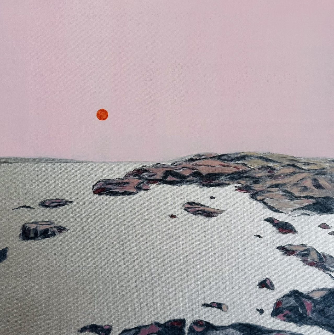 Orange sunset in a soft pink sky overlooking rocks and an ethereal silver metallic water