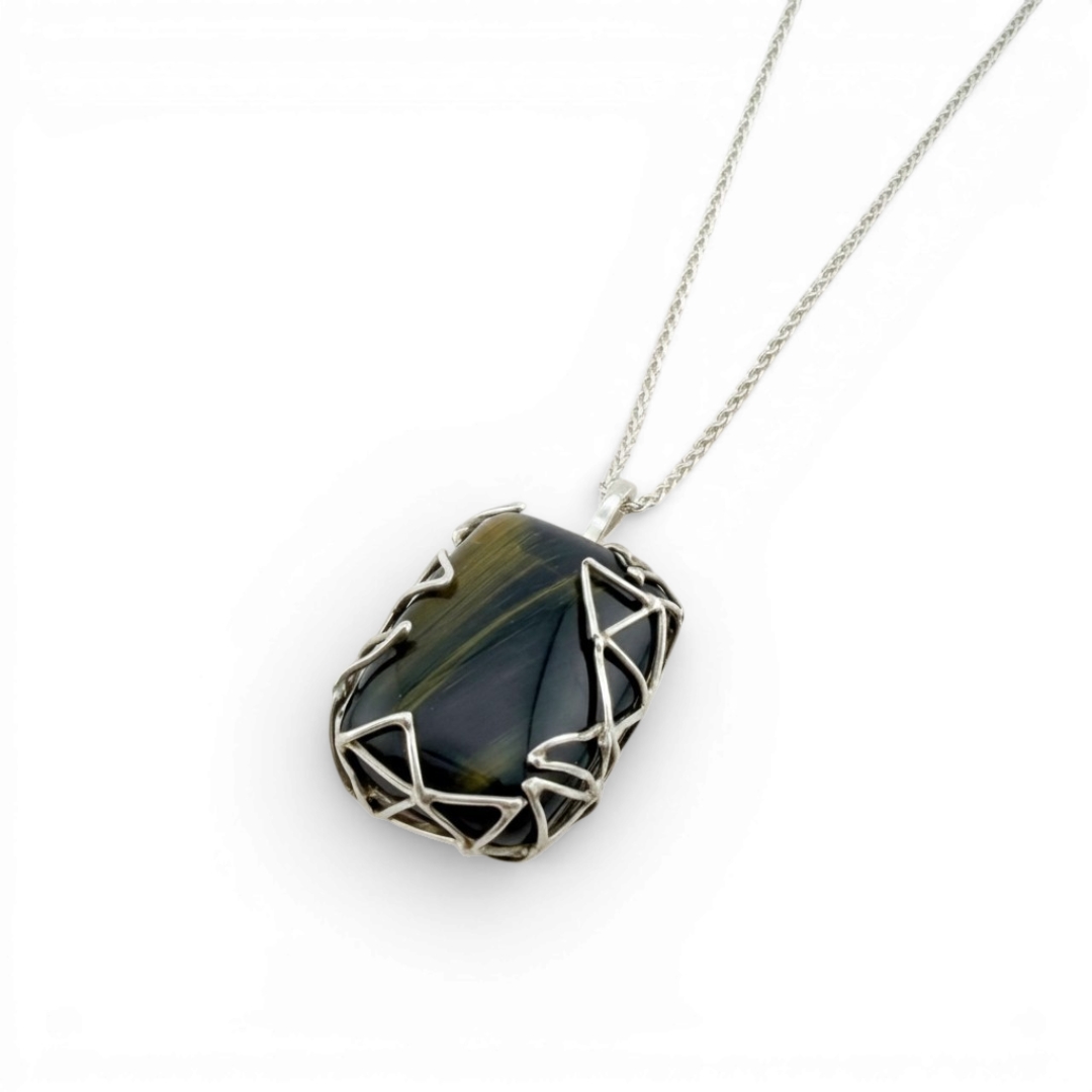 Sterling silver pendant featuring a textured metal pattern hugging a natural blue tiger eye gemstone.